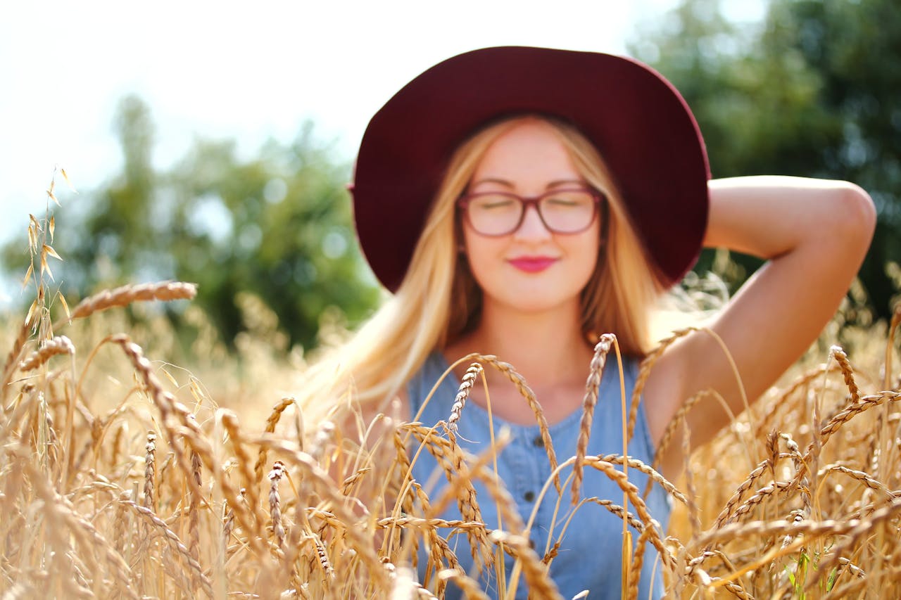 Woman Holding Her Cap on Her Head While Smiling